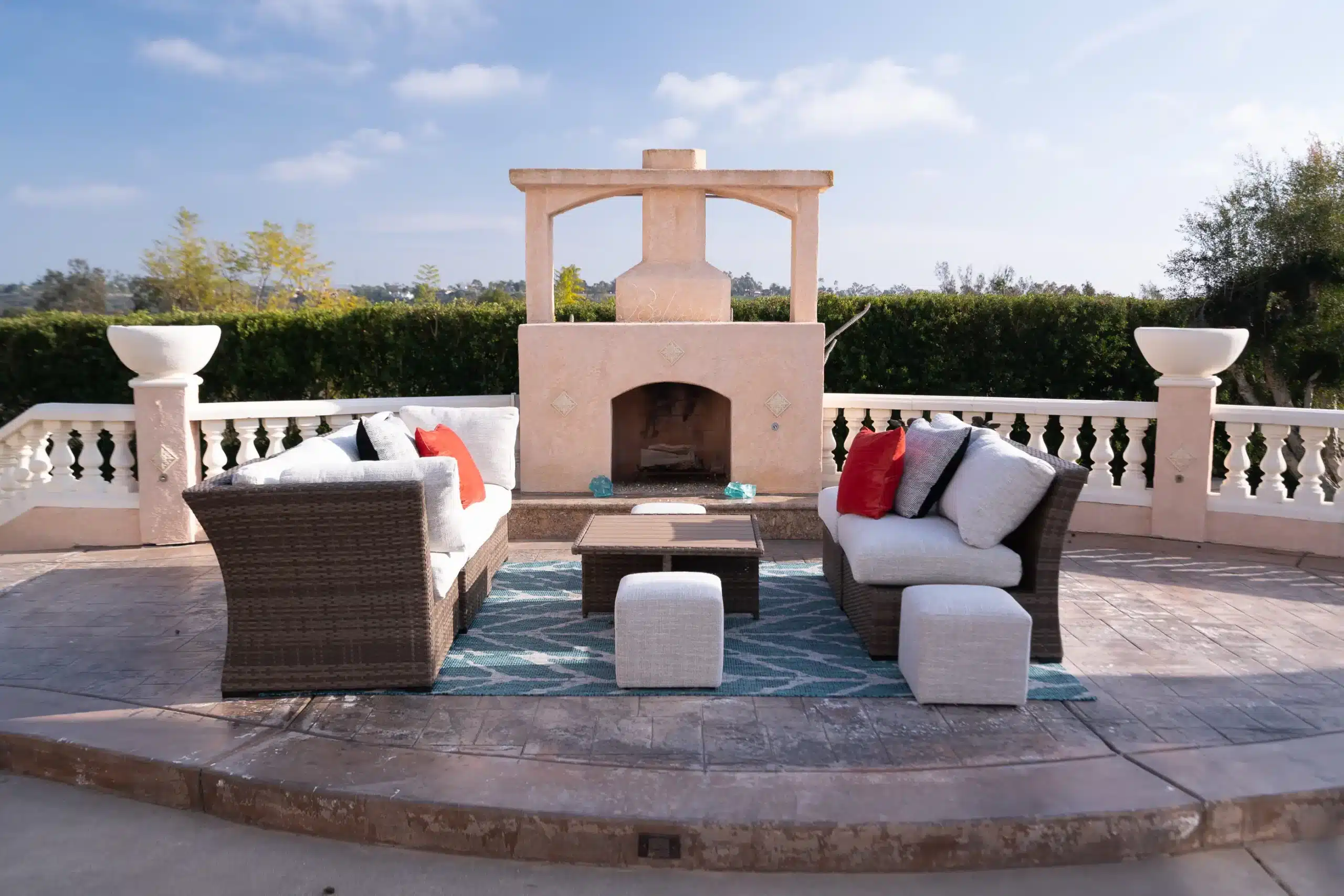 An outside sitting area on the balcony. There are 2 couches and a table in the middle. There is also a fireplace that says 'Believe' on the top.