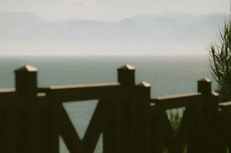 A shot looking over the ocean beach with a fence in the view