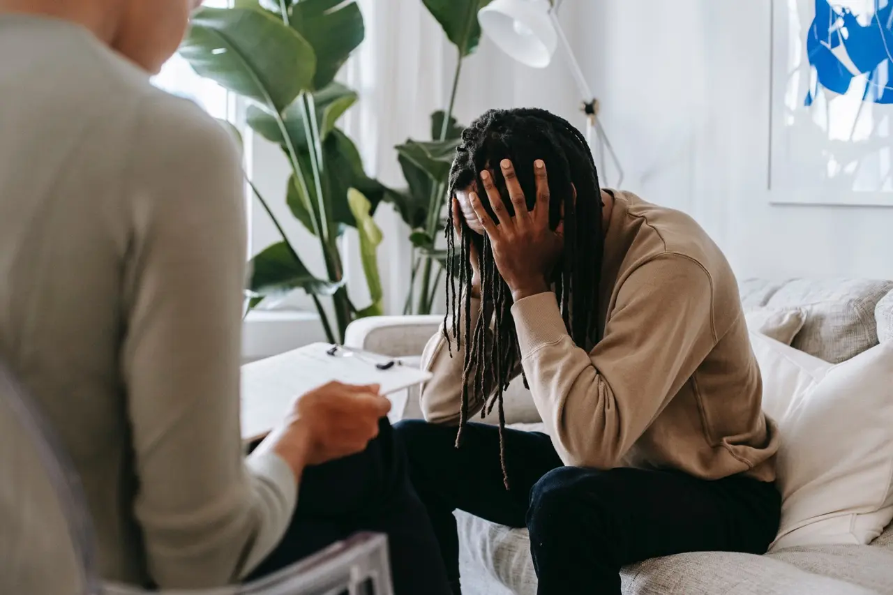 A resident sitting on a couch with his head in his hands during a trauma-informed therapy session