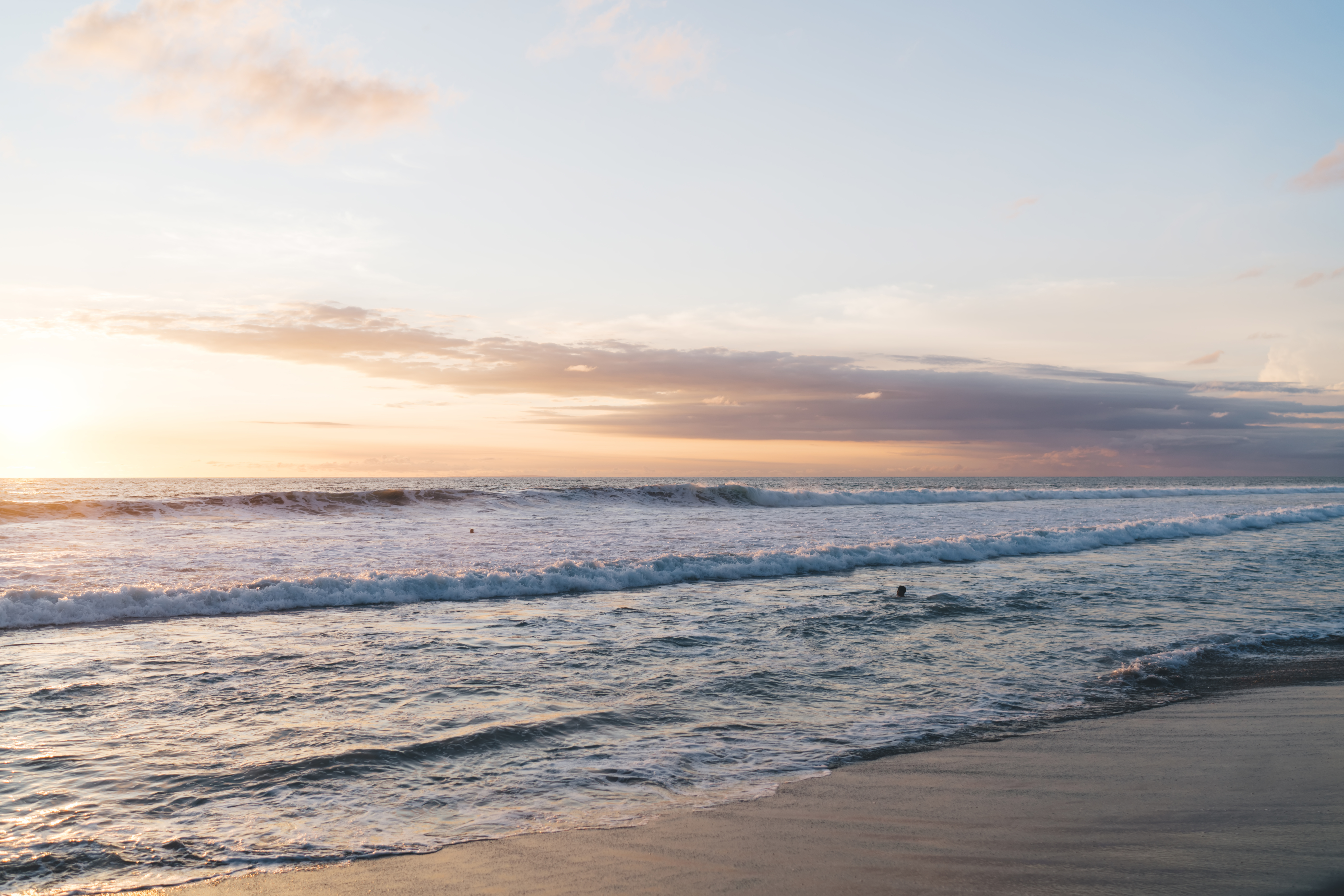 Amazing view from sandy coastline on ocean with waves at sunset light and cloudy sky in evening in hot exotic country